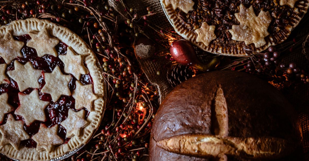 Two decorated pies and a loaf of bread surrounded by festive decorations, perfect for holiday celebrations.